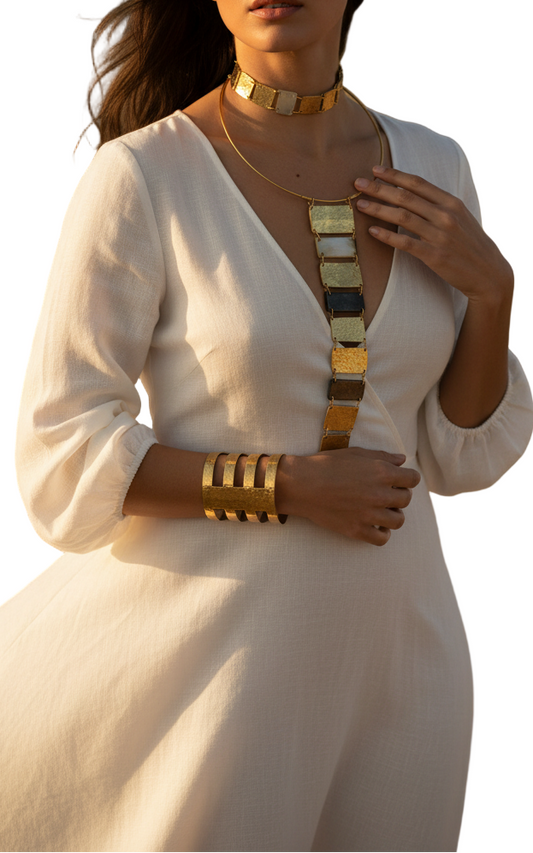 Woman in a white dress with gold jewelry standing in a desert landscape